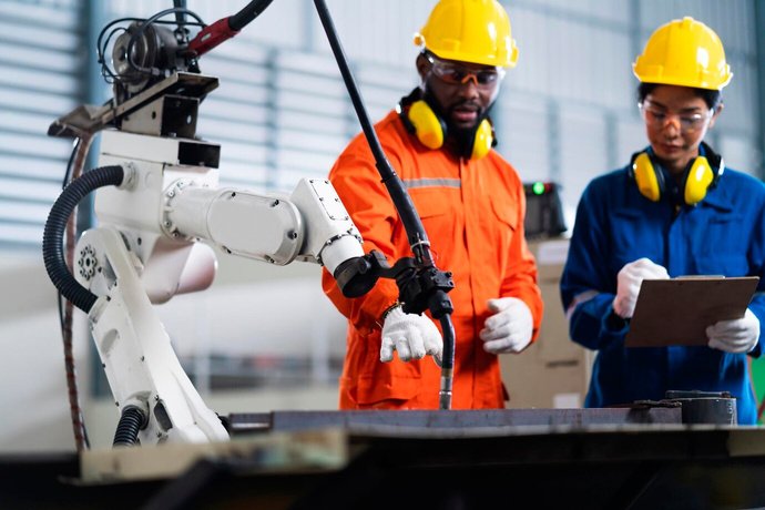 Factory floor workers in safety gear reviewing production output on a manufacturing line
