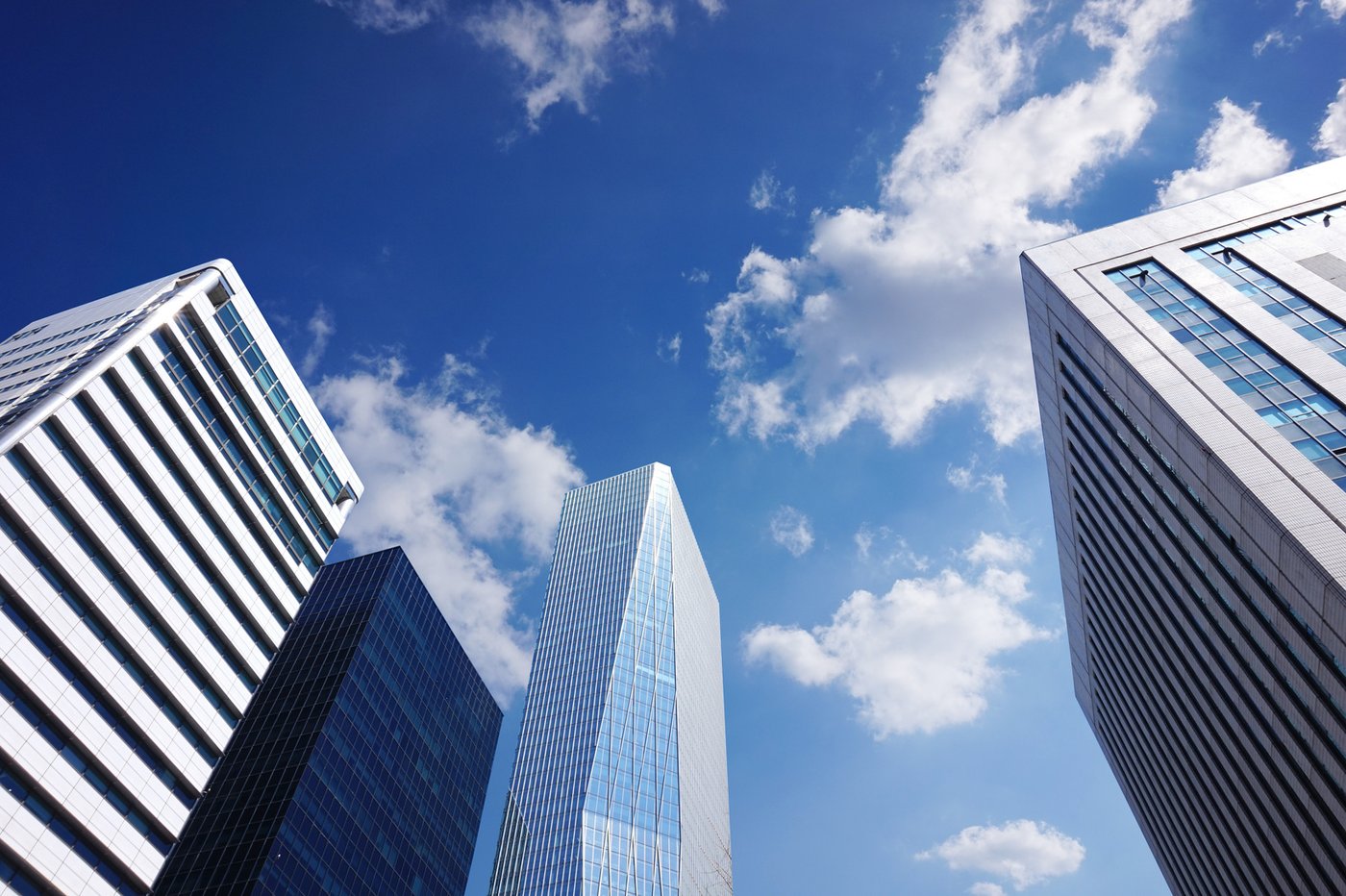 Modern commercial office towers viewed from street level against a blue sky